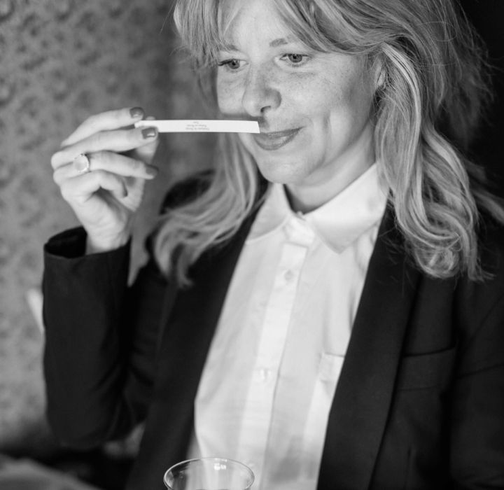 A black and white portrait of female perfumer Stéphanie de Bruijn, sniffing a perfume blotter