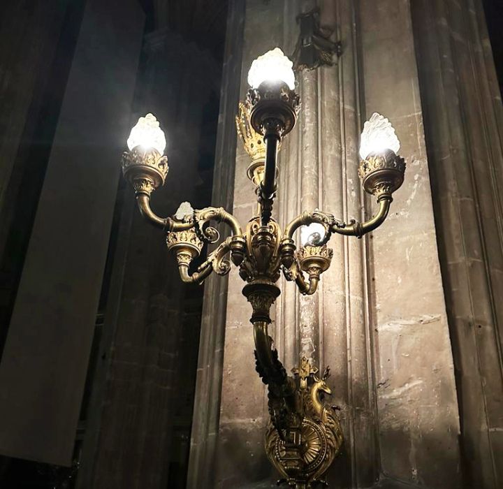 Pour illustrer l'histoire du parfum de niche Le Dieu Cerf, image d'un grand chandelier ancien doré dans un style rococo, accroché à un mur d'une église