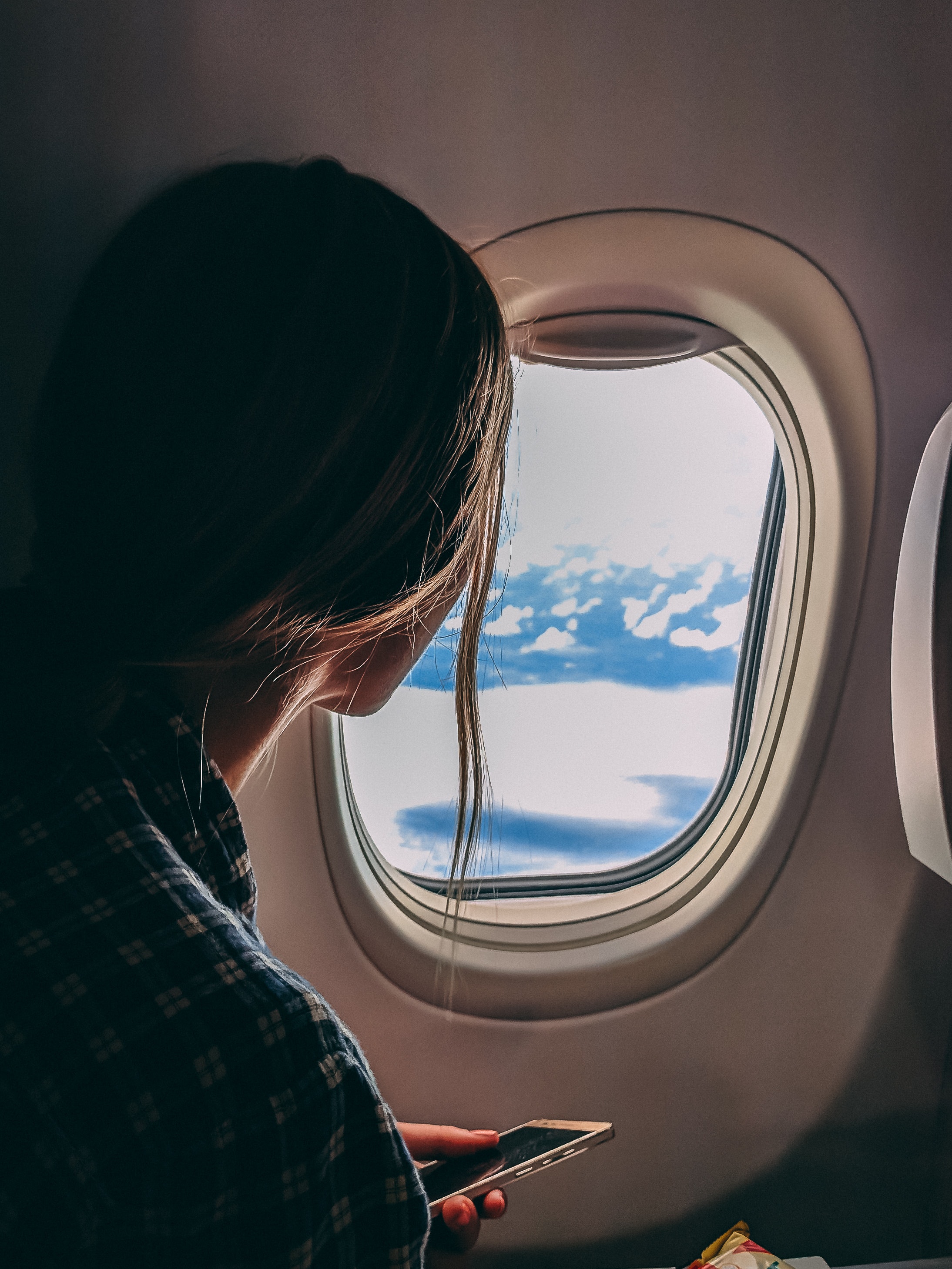 Une femme regarde par le hublot d'un avion de ligne.