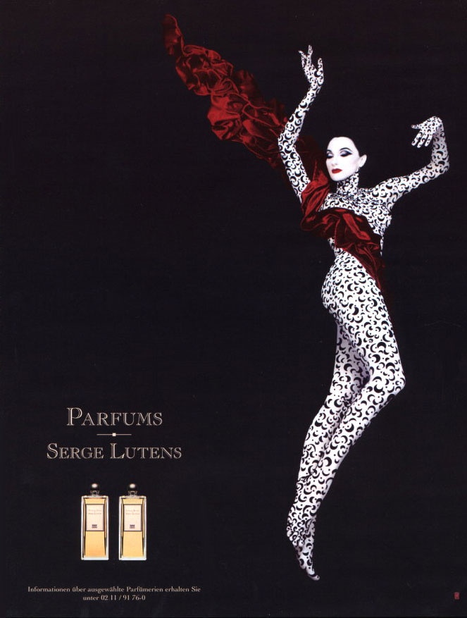 Publicité des années 80 pour les parfums SERGE LUTENS représentant une femme très pâle habillée d'un justaucorps blanc avec un motif d'arabesques et drapée d'une étole rouge - SCENTISSIME